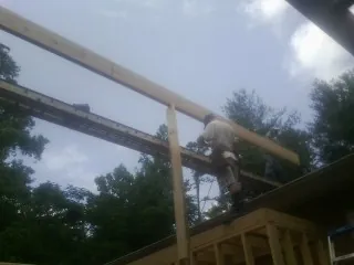 Carpenter setting a ridge beam over a new addition frame — Ice Dam Removal by Roofing Brothers in Bruington