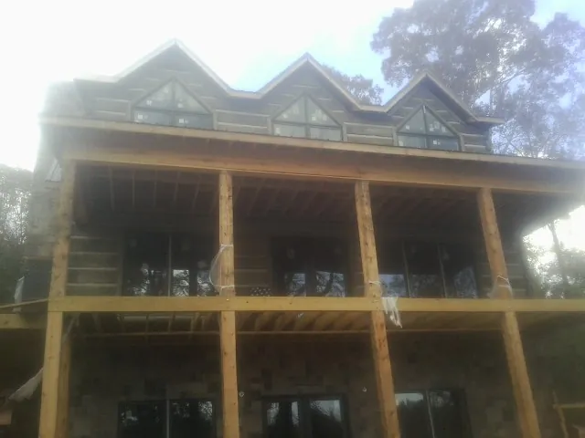 Dormers and porch framing on a large log home under construction — Roof Coating work by our crew in Bruington