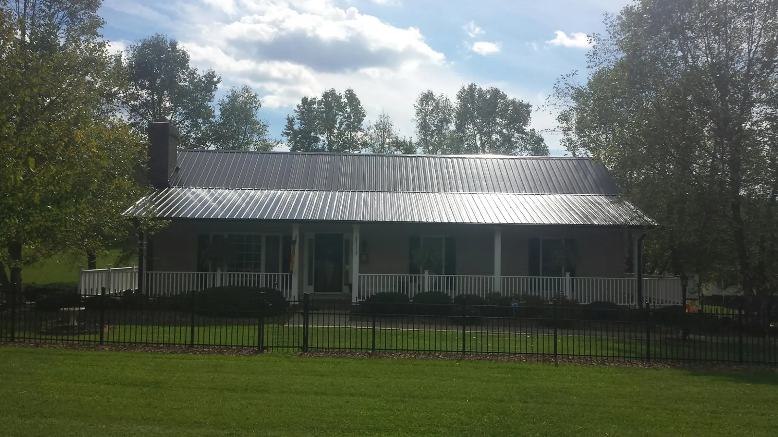 Gray metal roof on a brick ranch with a full width front porch — Gutter Guard Installation work by our crew in Bruington