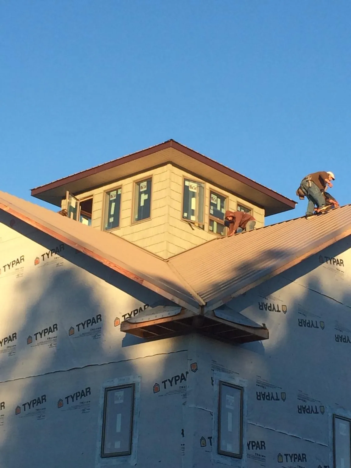 Roofers working around a rooftop cupola on a new metal roof at sunset — Roof Waterproofing in Bruington by Roofing Brothers